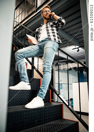 Happy young man is leaning on the railing indoors Happy young man is leaning on the railing indoors 61506013