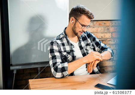 Young man checking the time in co-working space Young man checking the time in co-working space 61506377