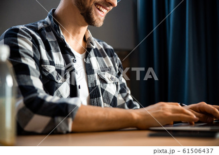 Happy young man sitting and typing on laptop Happy young man sitting and typing on laptop 61506437
