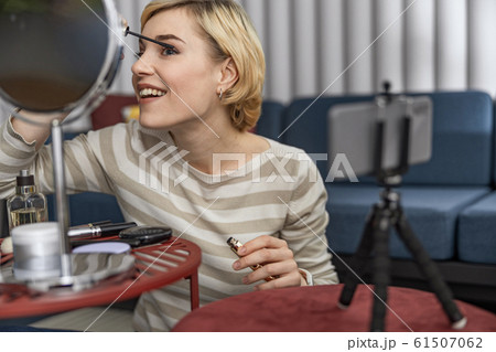 Happy young lady showing makeup on camera at home Happy young lady showing makeup on camera at home 61507062