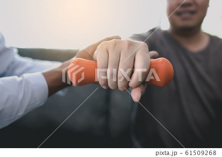 Asian physiotherapist helping a patient lifting 61509268