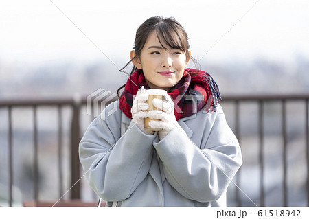 テイクアウトのカップを持つ若い女性　 61518942