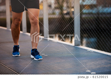 Male runner running in a city park over a bridge Male runner running in a city park over a bridge 61520015