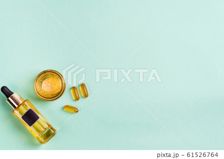 Beauty natural products with cosmetic cream, Omega-3 gel capsules, and oil in glass bottles on blue background. 61526764