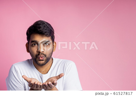 Portrait of handsome Indian guy standing on pink 61527817
