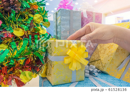 Woman hand taking a beautifully decorated gift box from a big stack of gifts near Christmas tree. 61528136