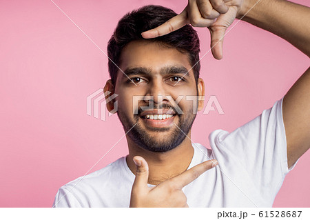 Portrait of handsome Indian guy standing on pink 61528687