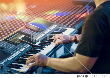 Musician play electronic keyboard synthesizers by using smartphone as guidelines for playing on the concert stage. Selective focus on smartphone. 61528752