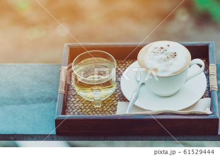 Hot coffee in a white cup and Chinese tea for a relaxing break for farmers in the afternoon on the terrace in the kale farm. Hot coffee in a white cup and Chinese tea for a relaxing break for farmers in the afternoon on the terrace in the kale farm. 61529444