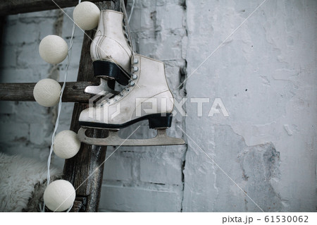 A pair of white leather sports skates hang on a 61530062
