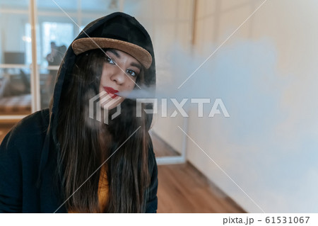 Vaping girl. Young hipster woman vape e-cig at the vapeshop. Hip-hop style. Closeup. 61531067