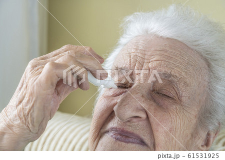 a senior woman applying eyedrops into her eyes 61531925