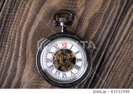 Vintage pocket watch on a chain lie on a wooden 61532496