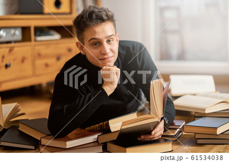 Young handsome student learns on the floor with books for exam  61534038