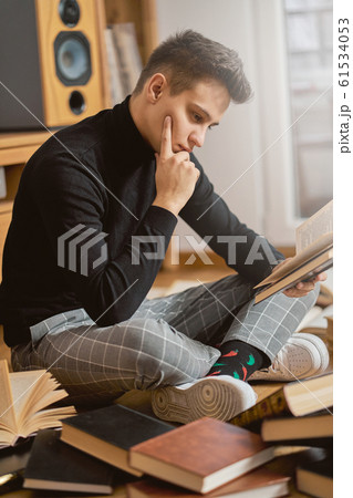 Young handsome student learns on the floor with books for exam  61534053