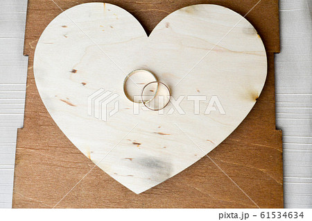 Gold wedding rings on a wooden heart. Gold wedding rings on a wooden heart. 61534634