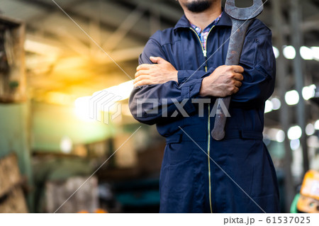 Portrait of Asian mechanic Fold over holding a wrench and smiling at truck and forklift garage. Industrial mechanic Engineer in Hard Hat 61537025