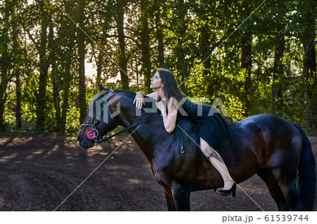Young slim woman brunette in a black dress sitting Young slim woman brunette in a black dress sitting 61539744