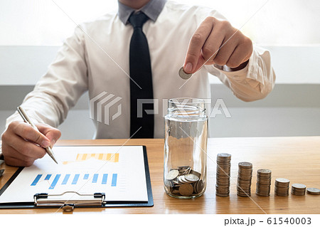 Business men laying coins down In a glass bottle next to the coin chart, expanding a successful and economical business for retirement concepts 61540003