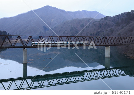 冬のダム湖を渡る電車 61540171