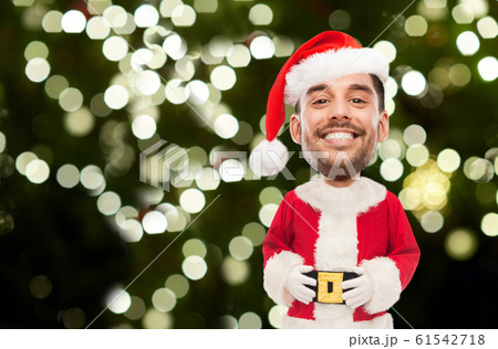 smiling man in santa costume over christmas tree smiling man in santa costume over christmas tree 61542718