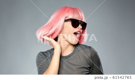 happy woman in pink wig and sunglasses dancing 61542765