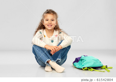 happy little girl with school bag sitting on floor happy little girl with school bag sitting on floor 61542804