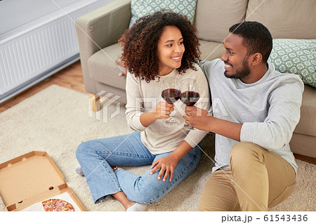 happy couple with wine and takeaway pizza at home 61543436