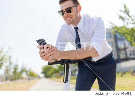 businessman with smartphone and electric scooter 61544091