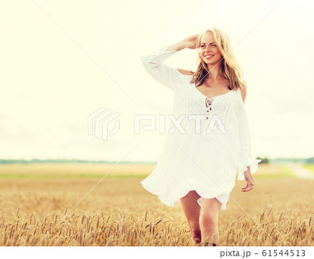 smiling young woman in white dress on cereal field 61544513