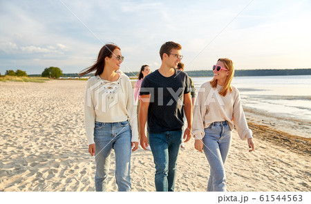 happy friends walking along summer beach 61544563