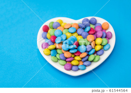 candies on heart shaped plate over blue background 61544564