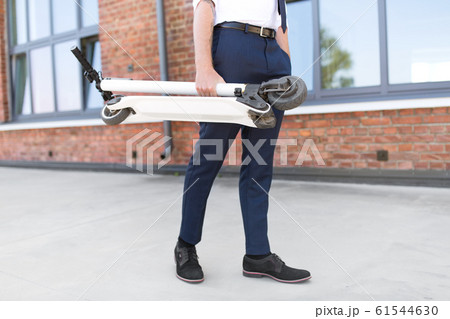 businessman with folding scooter on rooftop businessman with folding scooter on rooftop 61544630