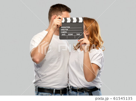 happy couple in white t-shirts with clapperboard happy couple in white t-shirts with clapperboard 61545135