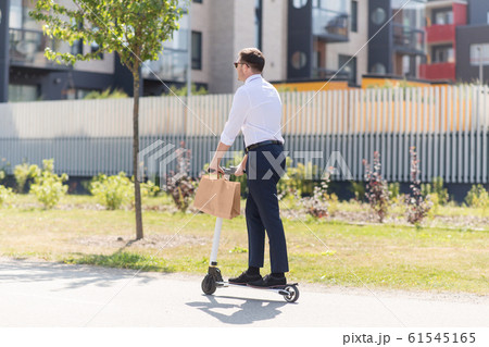 businessman with takeaway paper bag riding scooter 61545165