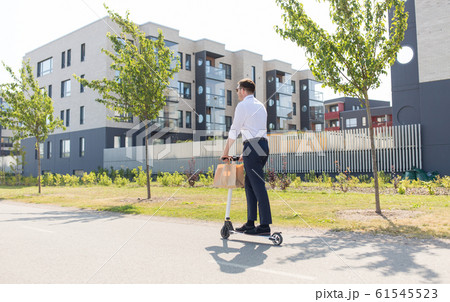 businessman with takeaway paper bag riding scooter 61545523