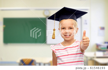 girl in mortarboard showing thumbs up at school 61546193
