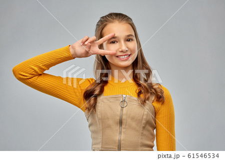 Smiling Young Teenage Girl Showing Peace Hand Signの写真素材