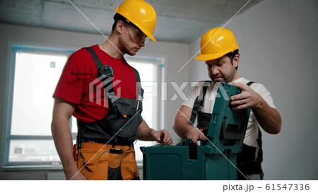 Two men workers pulling instruments out of the case 61547336