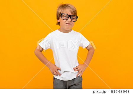 boy in a white T-shirt squinting in glasses on a yellow background with copy space boy in a white T-shirt squinting in glasses on a yellow background with copy space 61548943