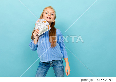 Little caucasian girl with long brow hair in blue hoody holds a lot of money isolated on blue Little caucasian girl with long brow hair in blue hoody holds a lot of money isolated on blue 61552191