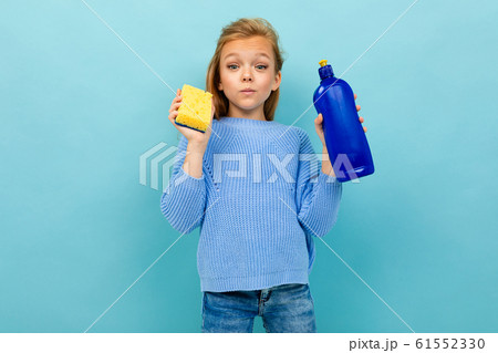 Girl is going to wash the dishes with washcloth and detergent isolated on blue background 61552330