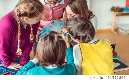 Pupils and teacher in geography class studying a globe Pupils and teacher in geography class studying a globe 61552866