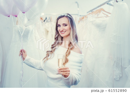 Bride to be in white with balloons in bridal wear shop 61552890