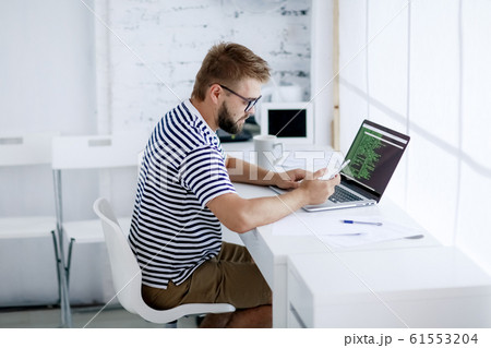 business man sitting at desk in office and looking at open laptop workstation. business man sitting at desk in office and looking at open laptop workstation. 61553204