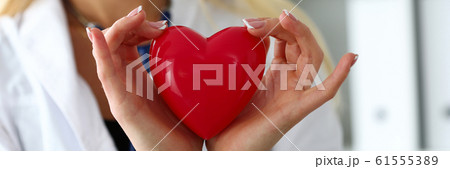 Female medicine doctor hands holding and covering red toy heart Female medicine doctor hands holding and covering red toy heart 61555389