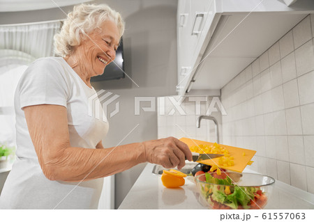 Senior woman making salad in kitchen. Senior woman making salad in kitchen. 61557063