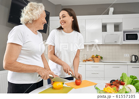 Senior woman cooking salad with granddaughter. 61557105