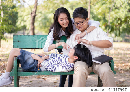 Happy Asian family and relaxing on the bench together in the public park Happy Asian family and relaxing on the bench together in the public park 61557997