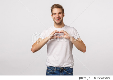 Dreamy and cute lovely boyfriend want make girlfriend surprise, confess, sharing his affection and positive emotions, make heart gesture near chest and smiling tender, white background 61558509